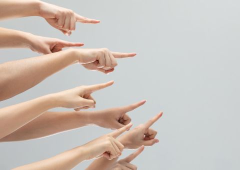 Nahaufnahme eines Bündels Hände, die auf etwas auf einem grauen Hintergrund mit Kopierraum zeigen