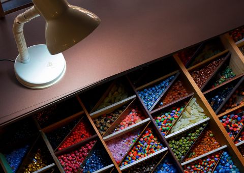 Schreibtischlampe beleuchtet sortierte Fächer mit bunten Perlen