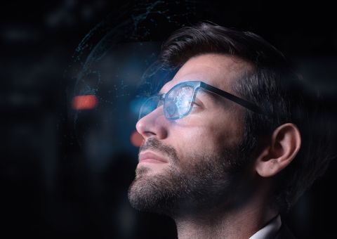 Ein Mann mit Brille blickt nach oben, reflektiert digitale Daten im futuristischen Licht.