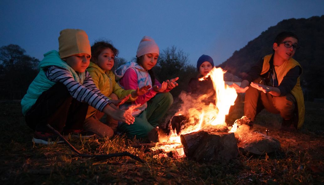 Kinder machen nach einer Wanderung ein Picknick am Lagerfeuer